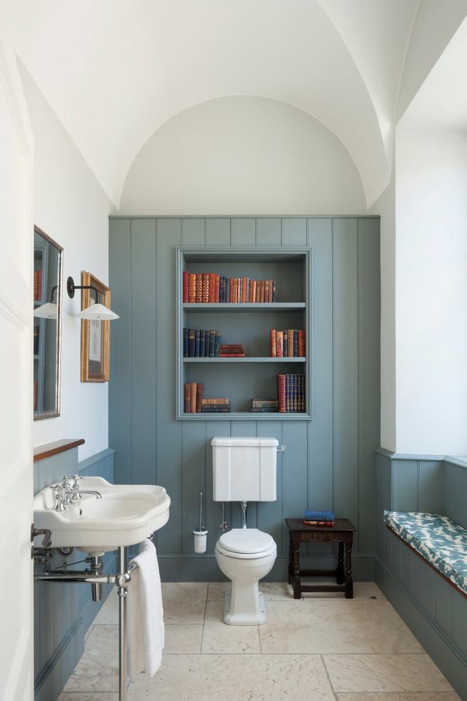 Small traditional powder room in London with a two-piece toilet, multi-coloured walls, a console sink, blue cabinets and beige floor.