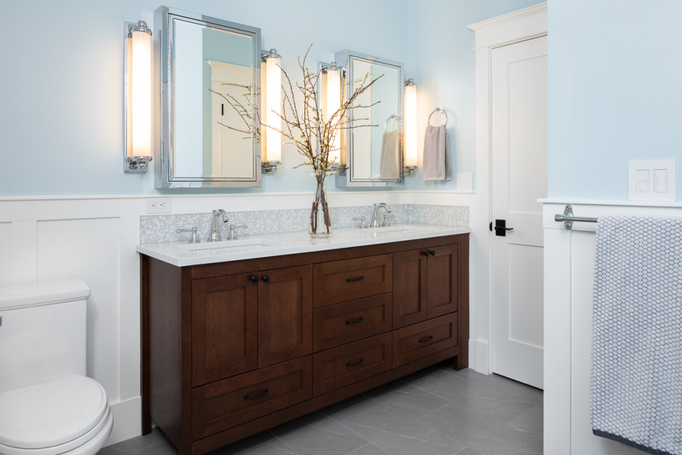 This is an example of a large transitional master bathroom in Seattle with furniture-like cabinets, dark wood cabinets, a freestanding tub, an alcove shower, a one-piece toilet, white tile, porcelain tile, blue walls, porcelain floors, an undermount sink, engineered quartz benchtops, grey floor, a hinged shower door, white benchtops, a niche, a double vanity, a freestanding vanity and decorative wall panelling.
