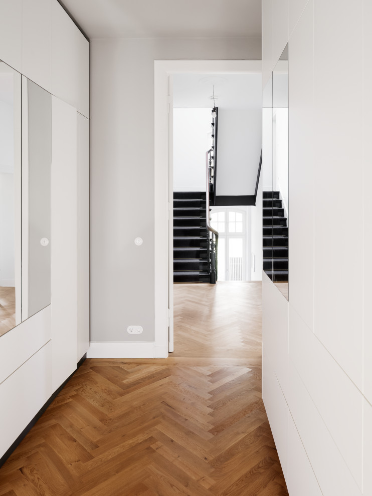 Built-in closet - mid-sized contemporary medium tone wood floor and brown floor built-in closet idea in Berlin with flat-panel cabinets and white cabinets