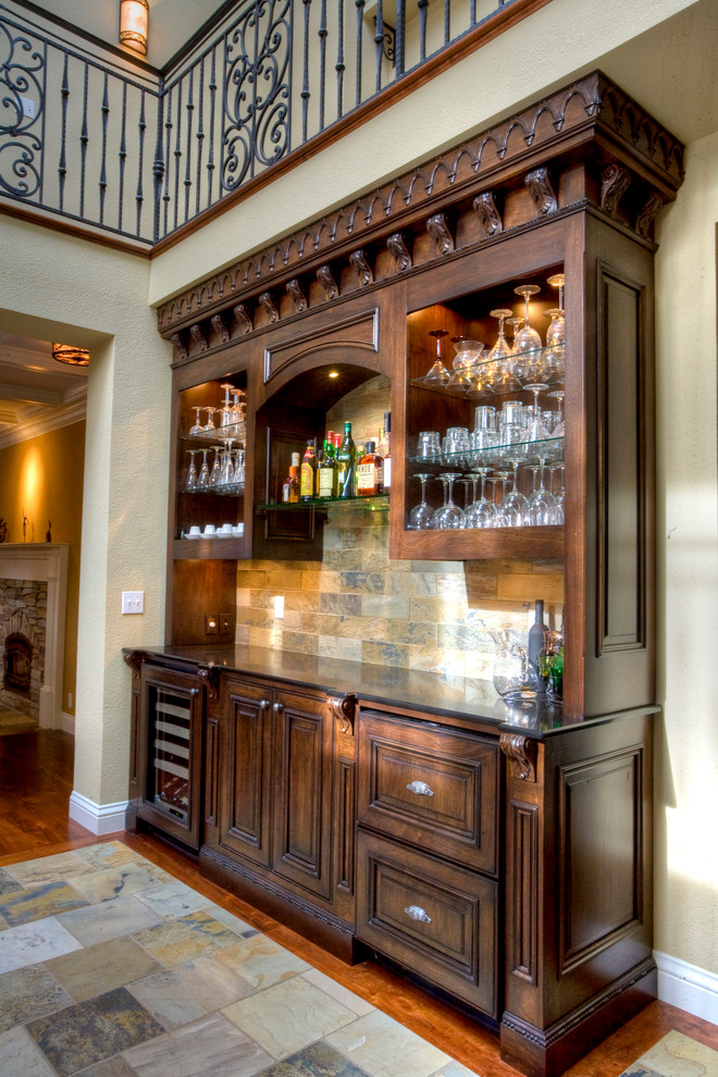 This is an example of a mid-sized traditional single-wall wet bar in San Francisco with no sink, recessed-panel cabinets, dark wood cabinets, quartz benchtops, brown splashback, stone tile splashback, slate floors and multi-coloured floor.