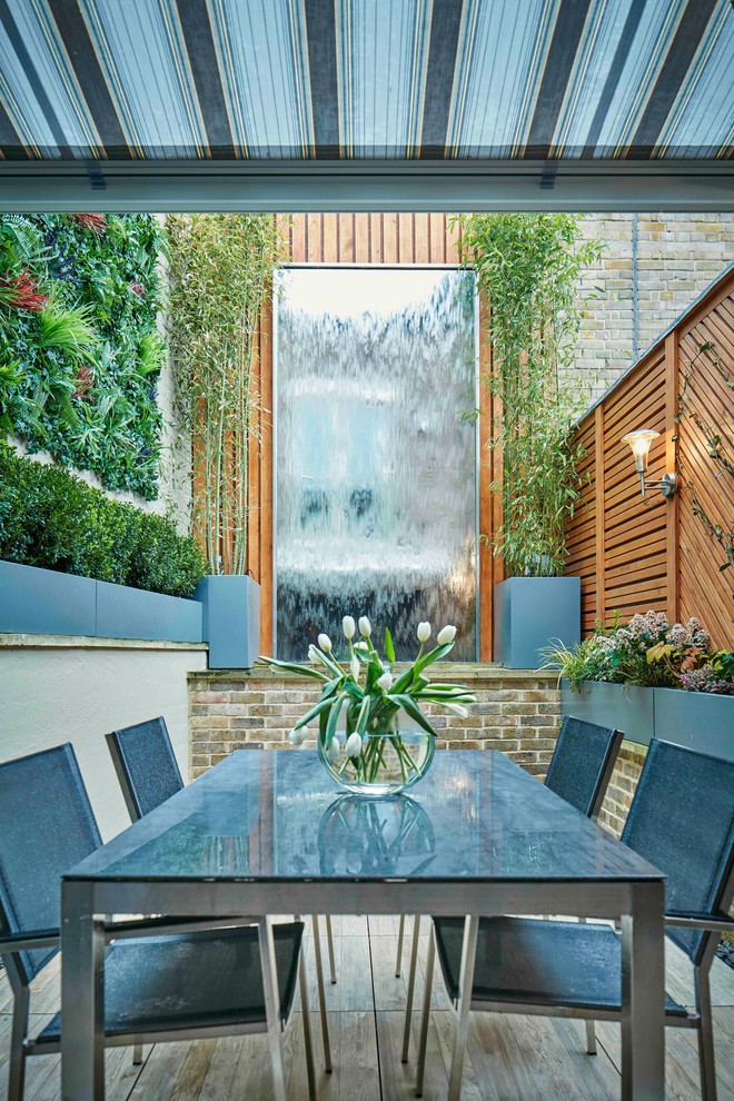 Photo of a small contemporary courtyard patio in London with a water feature and decking.