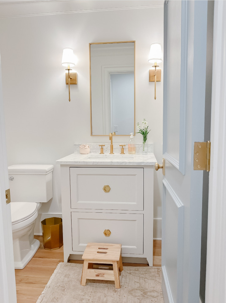 Inspiration pour un WC et toilettes traditionnel avec un placard à porte affleurante, des portes de placard blanches, un mur blanc, parquet clair, un lavabo encastré, un plan de toilette en marbre, un plan de toilette blanc et meuble-lavabo sur pied.