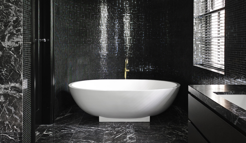 Design ideas for an expansive contemporary master wet room bathroom in Orange County with flat-panel cabinets, black cabinets, a freestanding tub, a one-piece toilet, black tile, glass sheet wall, black walls, marble floors, an undermount sink, marble benchtops, black floor and a sliding shower screen.