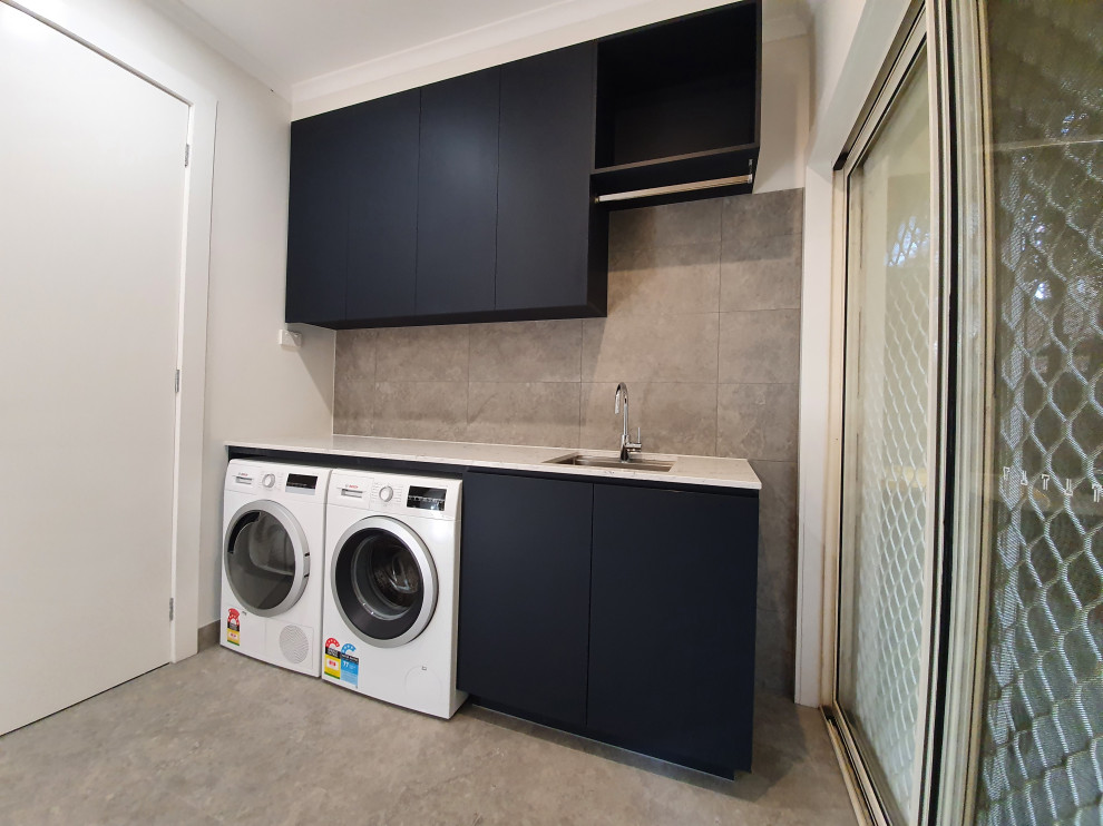 This is an example of a mid-sized contemporary single-wall dedicated laundry room in Melbourne with an undermount sink, quartz benchtops, grey splashback, porcelain splashback, grey walls, porcelain floors, a side-by-side washer and dryer and grey floor.