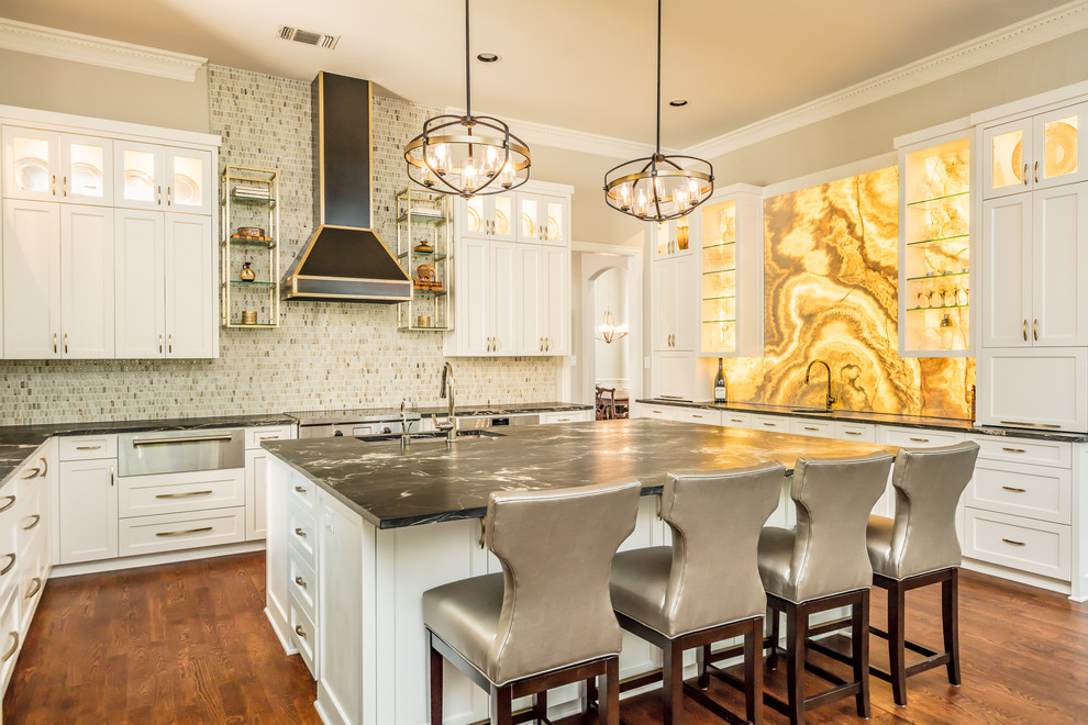 Photo of a large transitional u-shaped eat-in kitchen in Dallas with an undermount sink, shaker cabinets, white cabinets, granite benchtops, multi-coloured splashback, stainless steel appliances, with island, brown floor, black benchtop, mosaic tile splashback and medium hardwood floors.