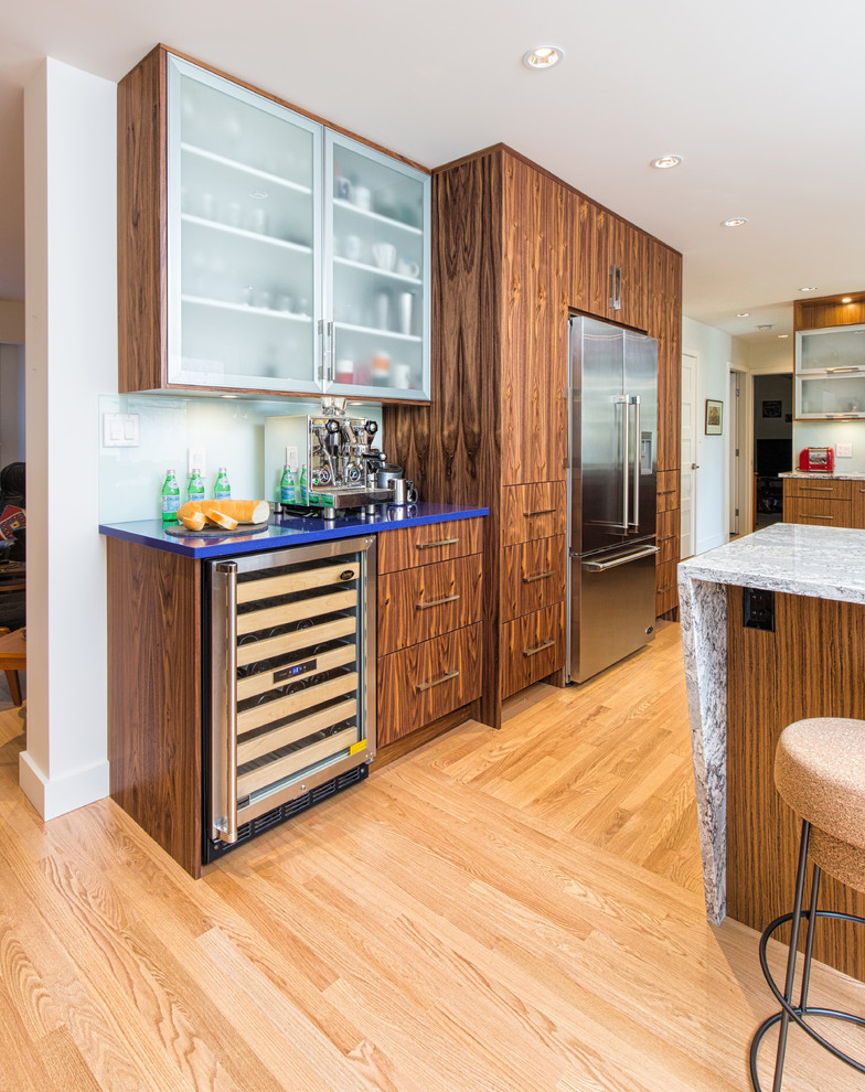 Midcentury u-shaped eat-in kitchen in Vancouver with an undermount sink, glass-front cabinets, medium wood cabinets, quartz benchtops, blue splashback, glass tile splashback, stainless steel appliances, light hardwood floors and a peninsula.