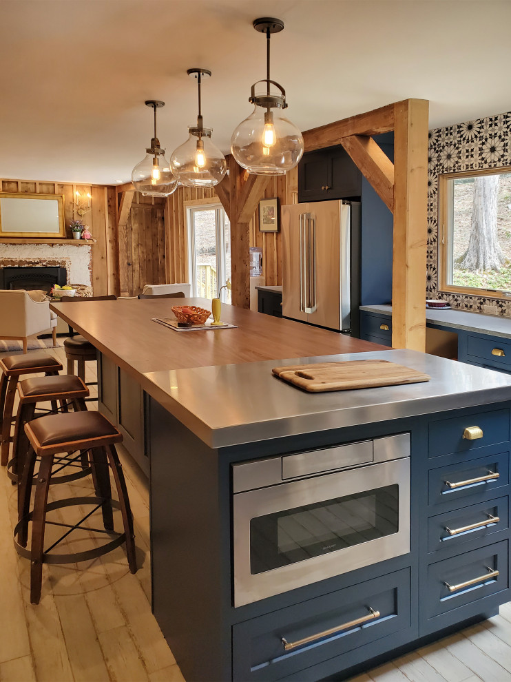 Photo of an eclectic kitchen in New York with a farmhouse sink, beaded inset cabinets, blue cabinets, concrete benchtops, stainless steel appliances, light hardwood floors, with island, beige floor and brown benchtop.