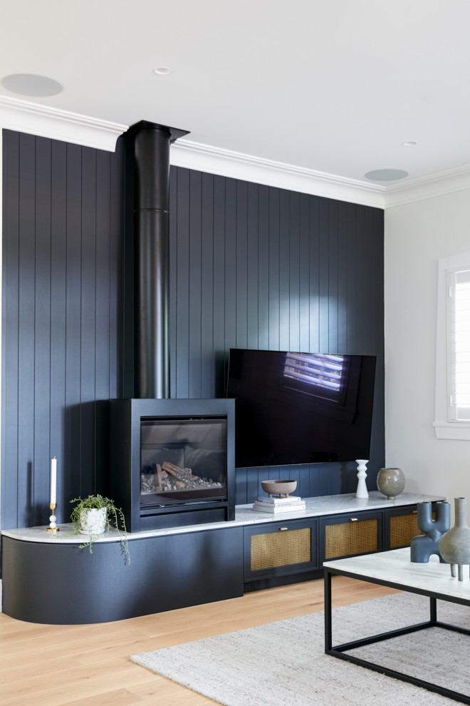 Inspiration pour un salon design de taille moyenne et ouvert avec un mur noir, parquet clair, une cheminée standard, un manteau de cheminée en bois, un téléviseur fixé au mur et un sol marron.