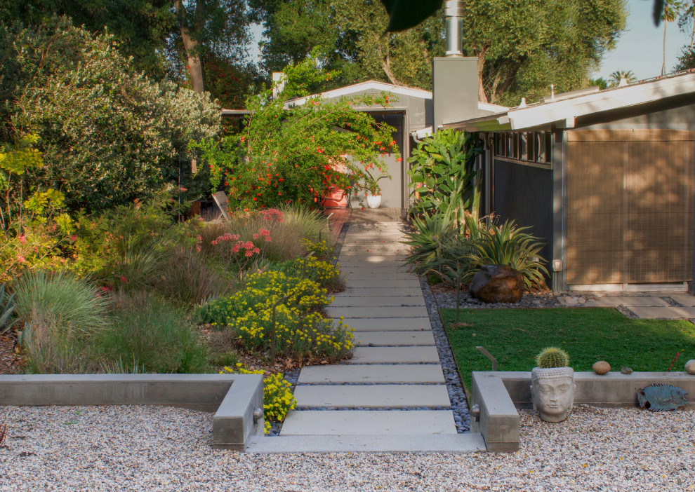 This is an example of a mid-sized mid-century modern partial sun front yard concrete paver and metal fence landscaping for winter.
