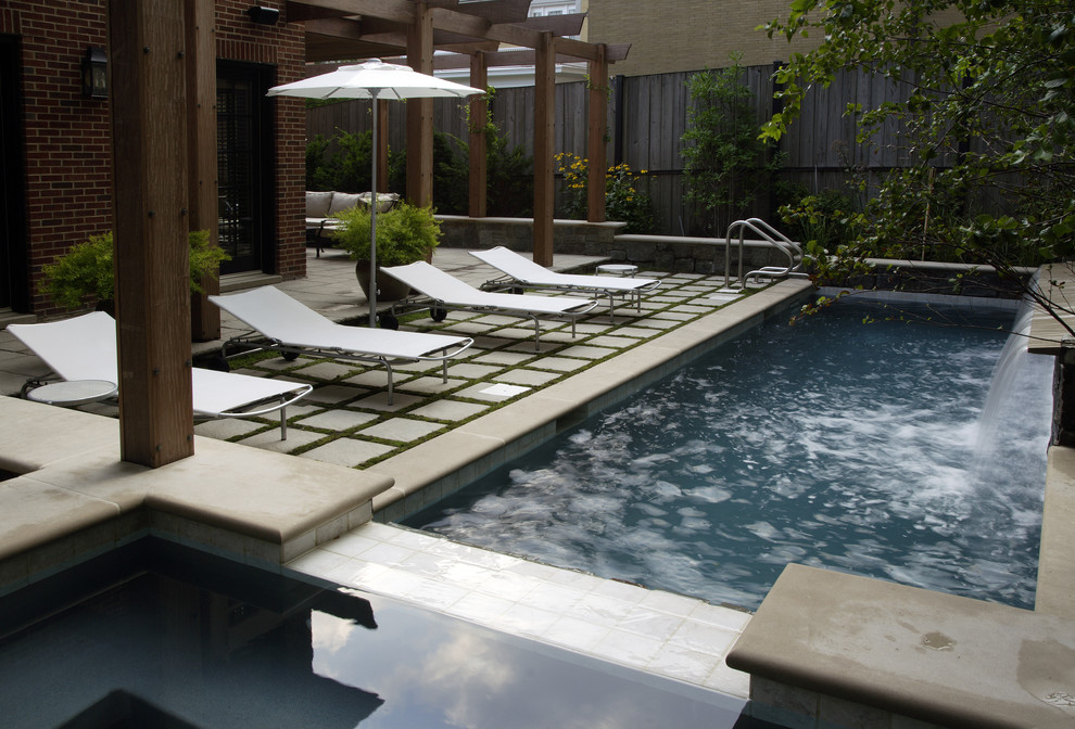 Inspiration for a mid-sized contemporary backyard rectangular infinity pool in Chicago with natural stone pavers and a water feature.