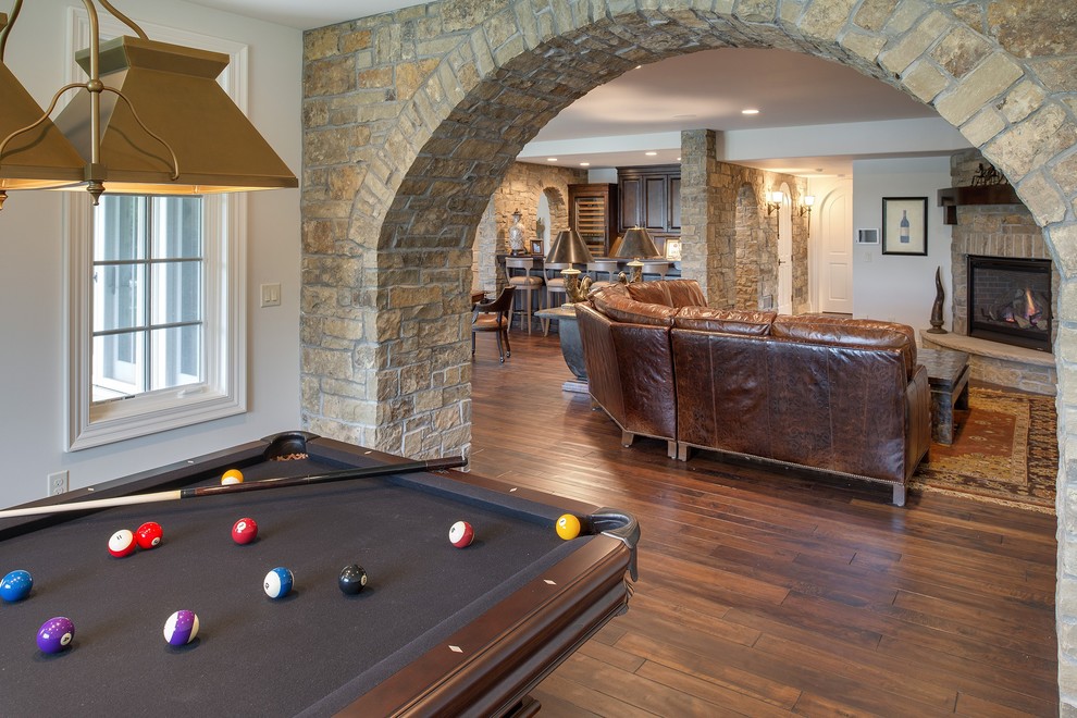 Photo of a traditional walk-out basement in Minneapolis with white walls, dark hardwood floors, a corner fireplace and a stone fireplace surround.