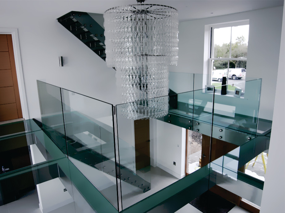 Photo of a large modern glass u-shaped staircase in Toronto with metal railing and panelled walls.