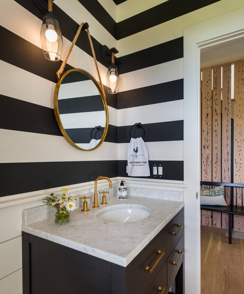 Inspiration for a beach style powder room in Boston with flat-panel cabinets, black cabinets, multi-coloured walls, an undermount sink, grey benchtops, a freestanding vanity and wallpaper.