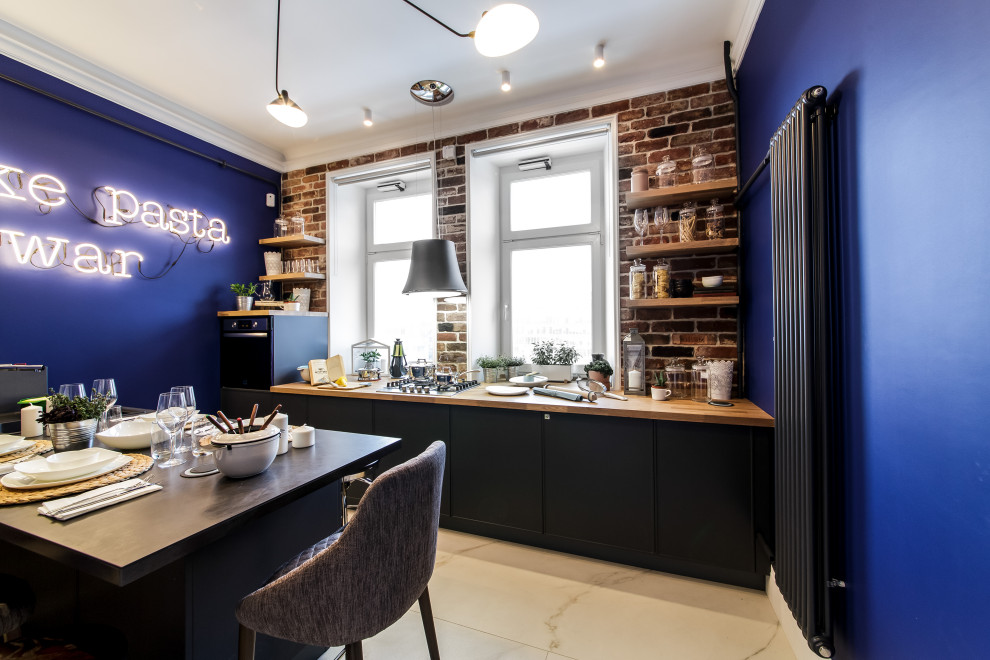 This is an example of a small contemporary galley kitchen/diner in Moscow with flat-panel cabinets, black cabinets, wood worktops, red splashback, brick splashback, black appliances, porcelain flooring, an island, white floors and beige worktops.