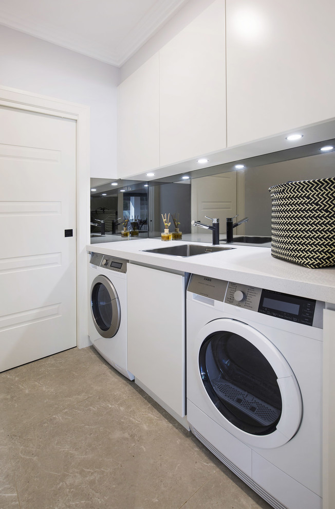 Small modern single-wall dedicated laundry room in Sydney with a single-bowl sink, flat-panel cabinets, white cabinets, quartz benchtops, white walls, limestone floors, a side-by-side washer and dryer and beige floor.