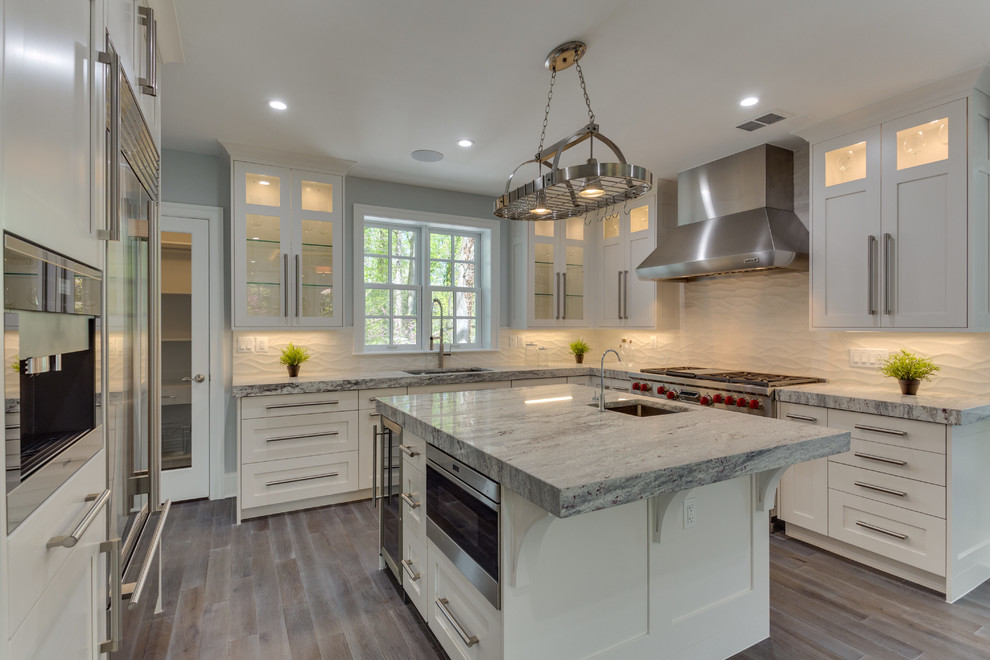 Large transitional l-shaped medium tone wood floor open concept kitchen photo in DC Metro with a single-bowl sink, shaker cabinets, white cabinets, marble countertops, white backsplash, porcelain backsplash, stainless steel appliances and an island