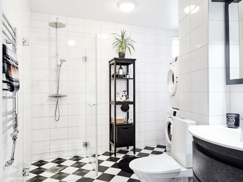 Design ideas for a scandinavian 3/4 bathroom in Gothenburg with flat-panel cabinets, black cabinets, a corner shower, a two-piece toilet, black and white tile, white tile, white walls, ceramic tile, ceramic floors, a vessel sink, a hinged shower door and a laundry.