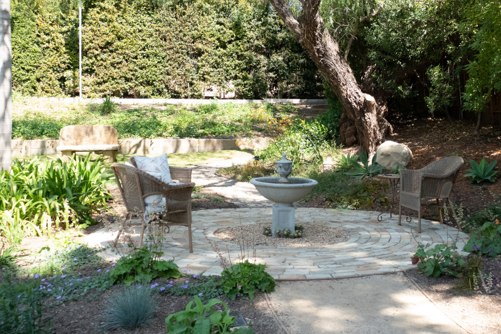Shabby chic-inspirerad inredning av en mellanstor bakgård i delvis sol som tål torka, med en fontän och naturstensplattor