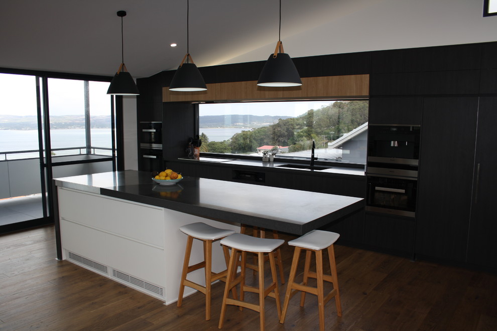 Design ideas for a large modern galley kitchen in Other with an undermount sink, flat-panel cabinets, dark wood cabinets, quartz benchtops, window splashback, stainless steel appliances, with island and black benchtop.