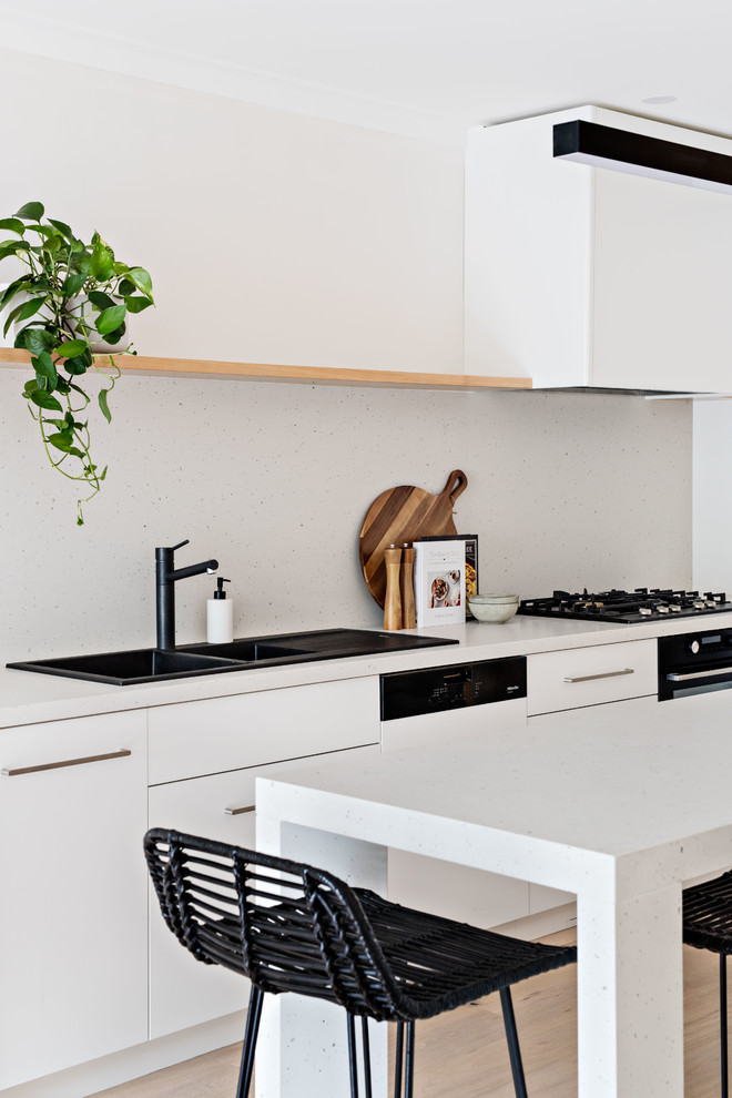 This is an example of a mid-sized contemporary galley eat-in kitchen in Sydney with a drop-in sink, white cabinets, quartz benchtops, white splashback, panelled appliances, with island and white benchtop.