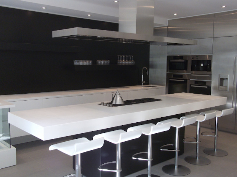 Large modern u-shaped eat-in kitchen in Toronto with a single-bowl sink, stainless steel appliances, porcelain floors, flat-panel cabinets, white cabinets, solid surface benchtops, black splashback and multiple islands.
