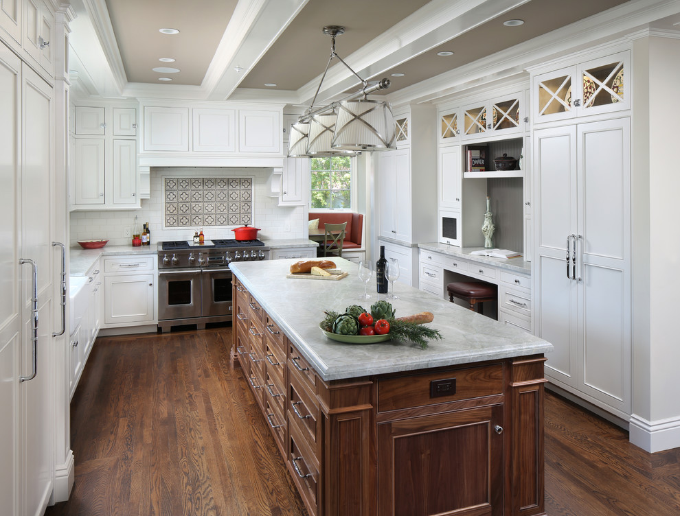 Design ideas for a large traditional u-shaped open plan kitchen in San Francisco with a farmhouse sink, recessed-panel cabinets, white cabinets, white splashback, stainless steel appliances, dark hardwood floors, with island, marble benchtops, subway tile splashback and brown floor.