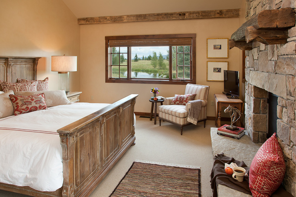 Photo of a country master bedroom in Other with carpet, a standard fireplace and a stone fireplace surround.
