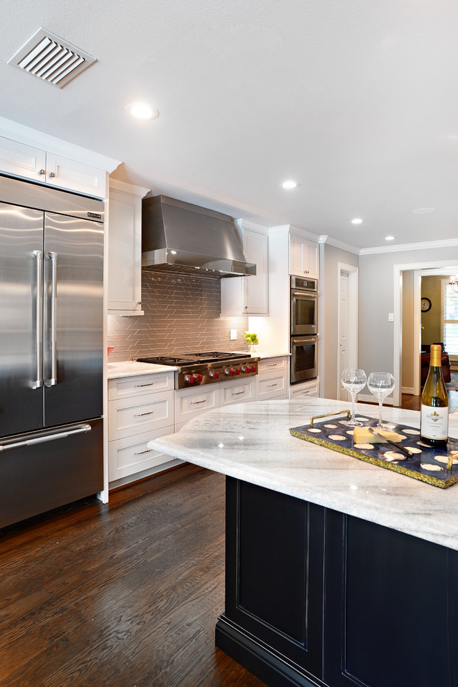 Large transitional single-wall dark wood floor eat-in kitchen photo in Dallas with a farmhouse sink, shaker cabinets, white cabinets, marble countertops, beige backsplash, glass tile backsplash, stainless steel appliances and an island