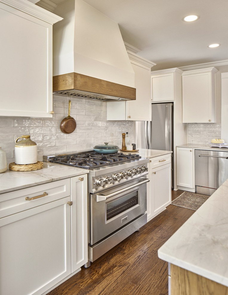 Design ideas for a mid-sized modern galley eat-in kitchen in Dallas with an integrated sink, shaker cabinets, white cabinets, quartzite benchtops, white splashback, ceramic splashback, stainless steel appliances, medium hardwood floors, with island, brown floor, white benchtop and recessed.