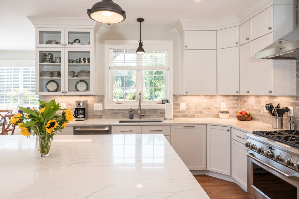 Inspiration for a large transitional u-shaped light wood floor open concept kitchen remodel in Baltimore with an undermount sink, shaker cabinets, white cabinets, quartz countertops, gray backsplash, ceramic backsplash, stainless steel appliances, an island and white countertops