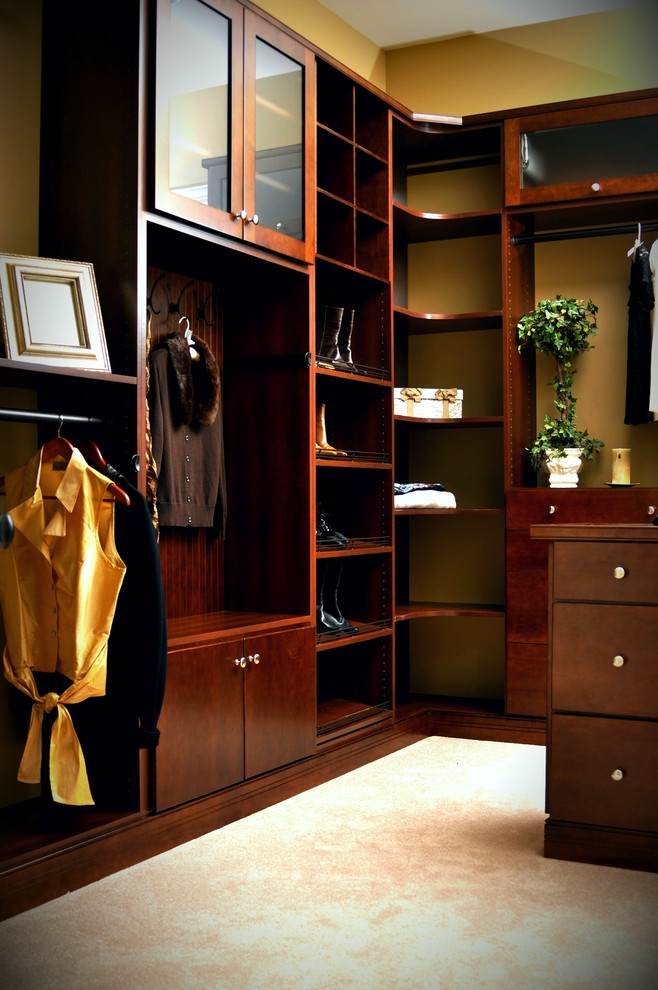 This is an example of an expansive traditional gender-neutral walk-in wardrobe in Philadelphia with medium wood cabinets, carpet and beige floor.