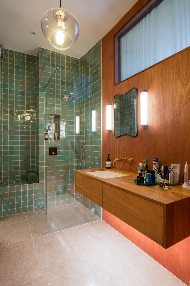 Photo of a large eclectic master bathroom in London with flat-panel cabinets, dark wood cabinets, a drop-in tub, an open shower, a one-piece toilet, green tile, ceramic tile, green walls, limestone floors, a drop-in sink, wood benchtops, green floor and an open shower.