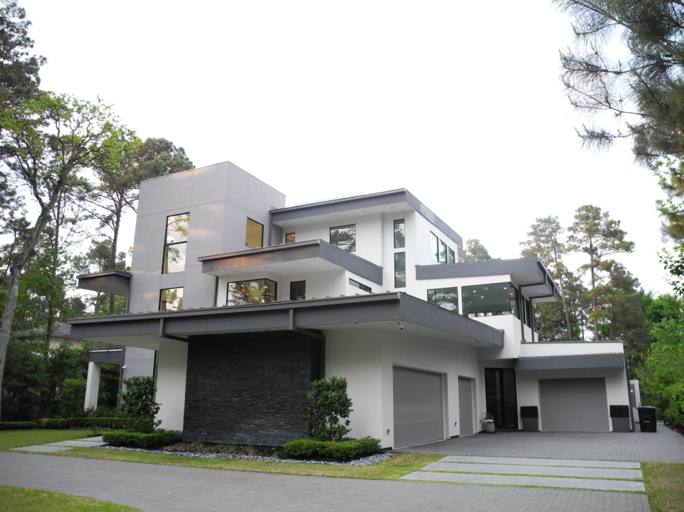 Cette photo montre une très grande façade de maison blanche moderne en stuc à deux étages et plus avec un toit plat, un toit en métal et un toit blanc.
