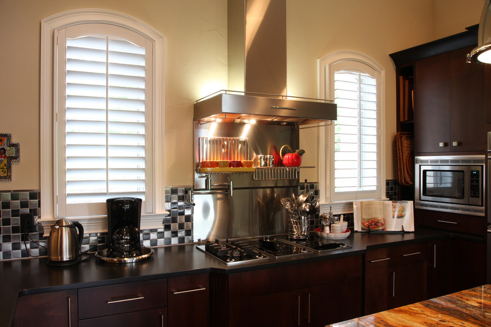 Transitional kitchen photo with flat-panel cabinets, dark wood cabinets, multicolored backsplash and stainless steel appliances