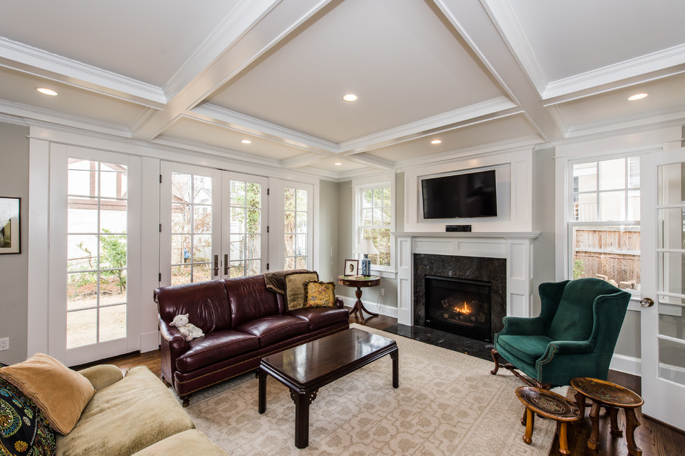 This is an example of a mid-sized traditional enclosed family room in DC Metro with a library, beige walls, dark hardwood floors, a standard fireplace, a wood fireplace surround and a wall-mounted tv.
