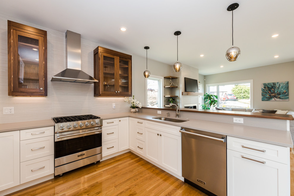 Design ideas for a contemporary u-shaped kitchen in Boston with a drop-in sink, shaker cabinets, white cabinets, quartzite benchtops, beige splashback, glass tile splashback, stainless steel appliances, medium hardwood floors and grey benchtop.