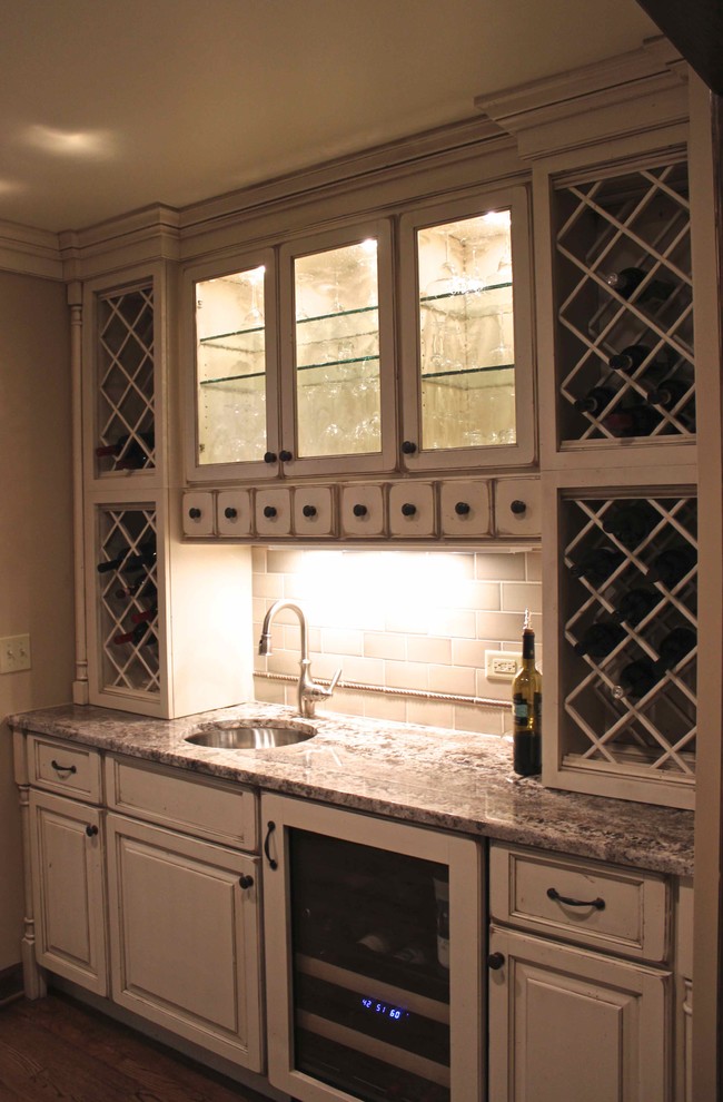 This is an example of a large traditional u-shaped kitchen pantry in Chicago with an undermount sink, raised-panel cabinets, distressed cabinets, granite benchtops, beige splashback, ceramic splashback, panelled appliances, dark hardwood floors, with island, brown floor and multi-coloured benchtop.