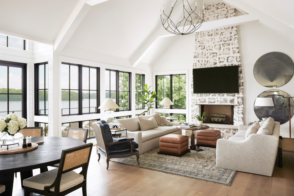 Inspiration for an expansive country open concept family room in Nashville with white walls, light hardwood floors, a standard fireplace, a wall-mounted tv, beige floor and vaulted.