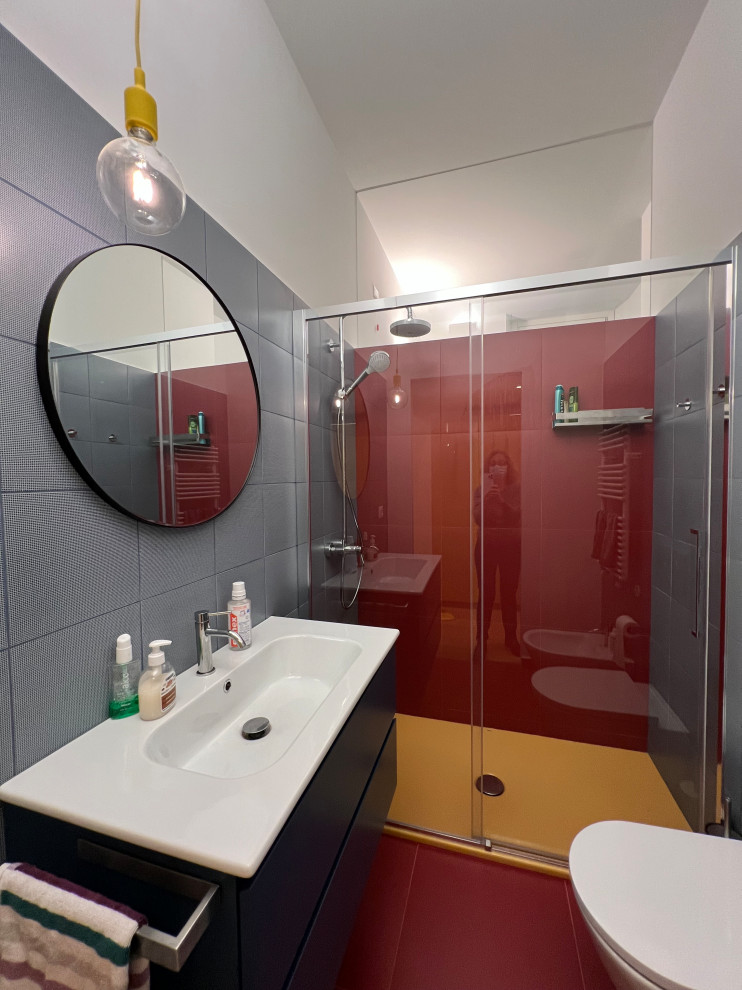 Foto på ett mellanstort funkis vit badrum för barn, med blå skåp, en kantlös dusch, en toalettstol med separat cisternkåpa, flerfärgad kakel, porslinskakel, vita väggar, klinkergolv i porslin, ett integrerad handfat, rött golv och dusch med skjutdörr