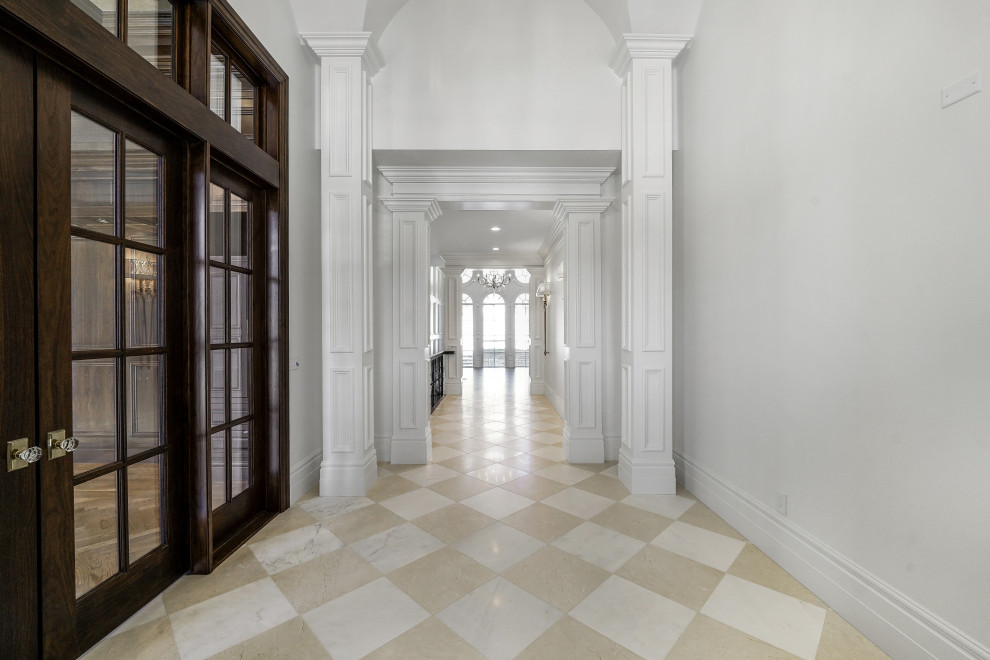 This is an example of a large foyer in Salt Lake City with white walls, marble floors, a double front door, a dark wood front door, white floor and vaulted.