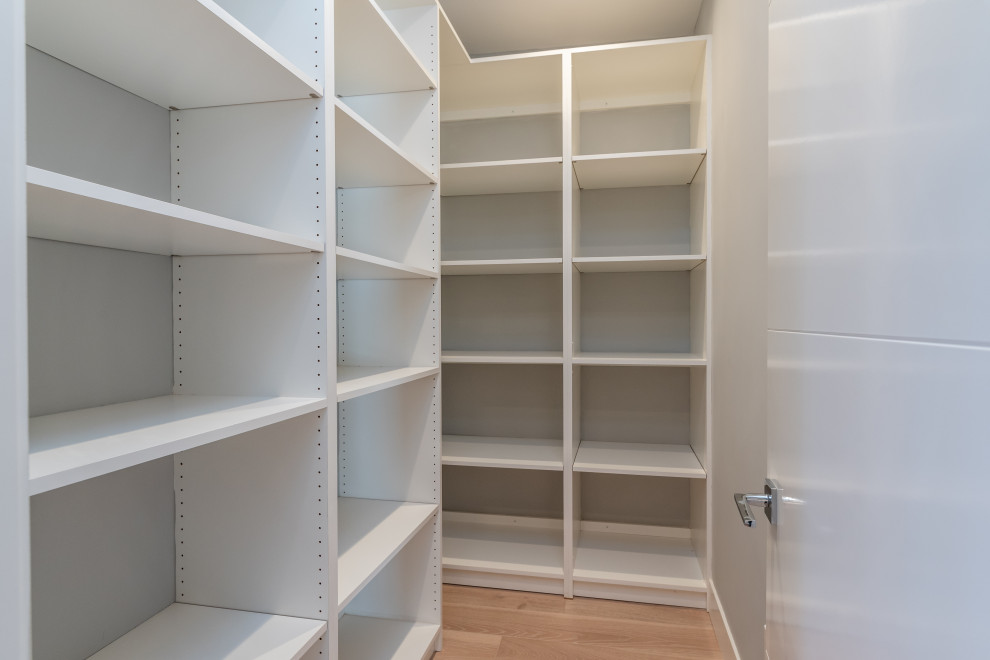 Design ideas for a large modern gender-neutral walk-in wardrobe in San Francisco with flat-panel cabinets, white cabinets, light hardwood floors and white floor.