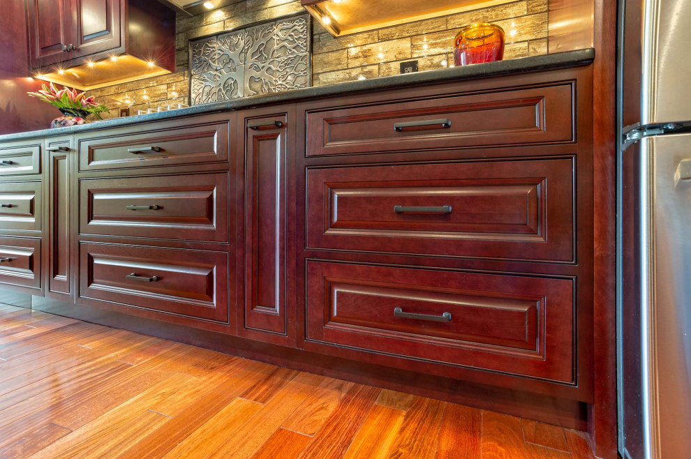 Inspiration for a large transitional single-wall light wood floor and brown floor eat-in kitchen remodel in Philadelphia with an undermount sink, raised-panel cabinets, red cabinets, granite countertops, brown backsplash, porcelain backsplash, stainless steel appliances, an island and brown countertops