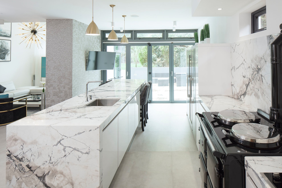 Inspiration for a mid-sized contemporary galley open plan kitchen in London with an integrated sink, flat-panel cabinets, white cabinets, marble benchtops, multi-coloured splashback, marble splashback, stainless steel appliances, porcelain floors, with island and grey floor.