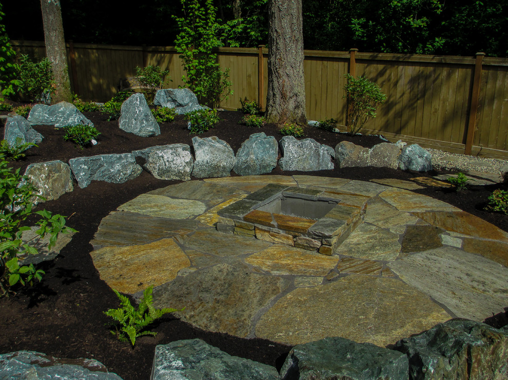 Inspiration for a mid-sized rustic partial sun backyard stone formal garden in Seattle with a fire pit for spring.
