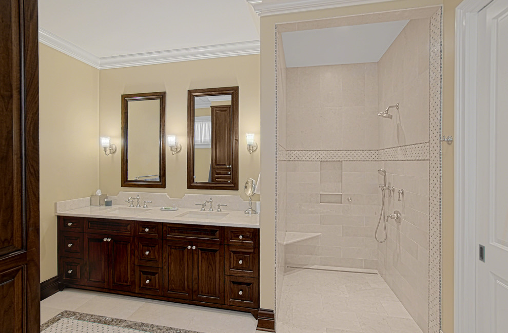 This is an example of a mid-sized traditional master bathroom in Chicago with recessed-panel cabinets, dark wood cabinets, a curbless shower, beige tile, porcelain tile, yellow walls, an undermount sink, engineered quartz benchtops, multi-coloured floor, an open shower, white benchtops, a double vanity and a built-in vanity.