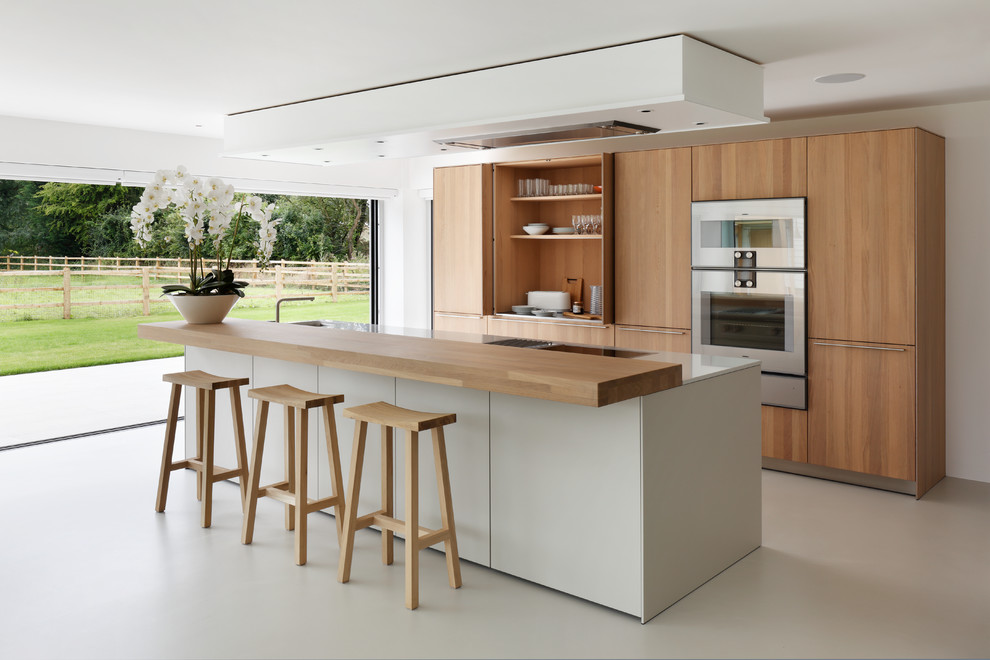 Scandinavian kitchen in London with flat-panel cabinets, light wood cabinets, with island and white floor.