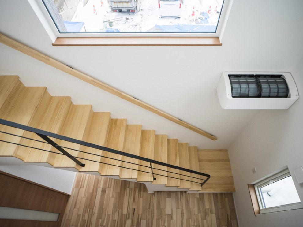 This is an example of a medium sized modern wood straight wood railing staircase in Other with wood risers, wallpapered walls and under stair storage.