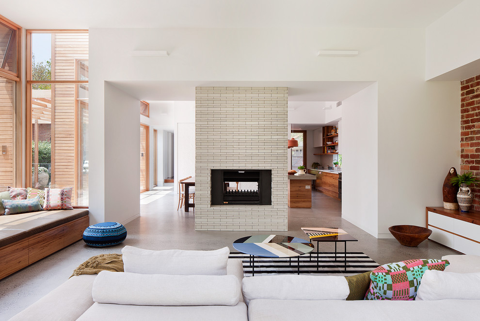 Inspiration for a mid-sized contemporary open concept living room in Melbourne with concrete floors, a two-sided fireplace, a tile fireplace surround and white walls.