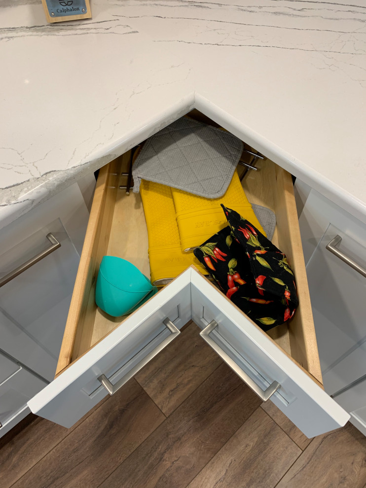 Inspiration for a large transitional u-shaped vinyl floor and brown floor open concept kitchen remodel with an undermount sink, shaker cabinets, white cabinets, quartz countertops, white backsplash, ceramic backsplash, stainless steel appliances, an island and white countertops