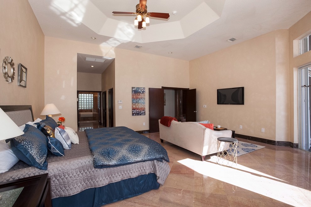 Large transitional master bedroom in Miami with beige walls and travertine floors.